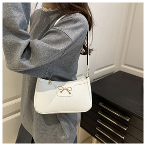 Detail of white bow shoulder bag in textured faux leather on a model for daily look