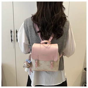 Detail of pink and white PU leather backpack with butterfly print and teddy bear charm