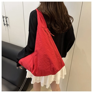 Detail view of a large red nylon tote bag with side zipper on a female model
