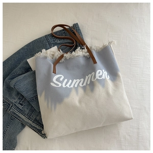 Detail of frayed edges and blue tie-dye canvas texture on the summer tote bag