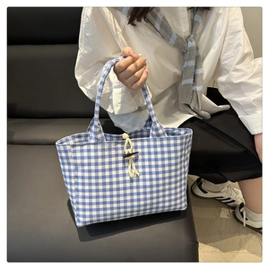 Dettaglio della borsa tote in tela a quadretti bianchi e blu con bottone in corno