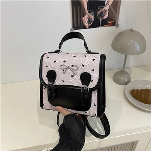 Sac à dos en jacquard rose avec motifs de nœuds noirs et ornement de nœud argenté