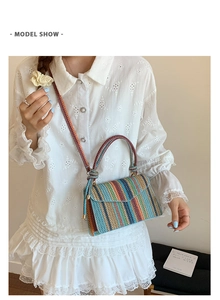 Colorful striped woven crossbody bag with triangular flap and top handle on a model