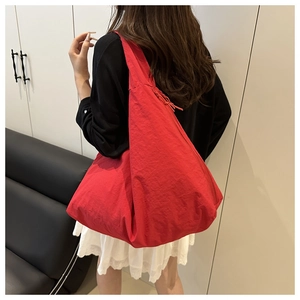 Detailed view of a red oversized slouchy tote bag featuring a knotted zipper puller