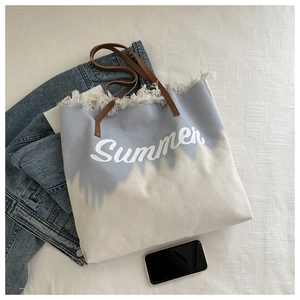 Close-up of blue gradient canvas tote bag with tassel fringe edges and Summer print