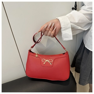 Close-up of red lychee pattern handbag featuring gold bow metal and flower charm