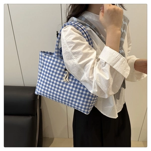 Dettaglio della borsa tote in tela a quadretti blu e bianchi con nappa decorativa