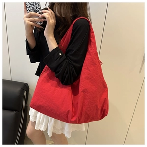 Large red hobo tote bag with pleated texture shown on shoulder for casual style