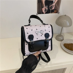 Sac à dos plissé rose avec garniture en cuir noir et boucle nœud argenté sur un bureau chic