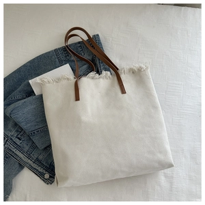 Detailed macro view of white canvas tote with stylish frayed edges and brown handles