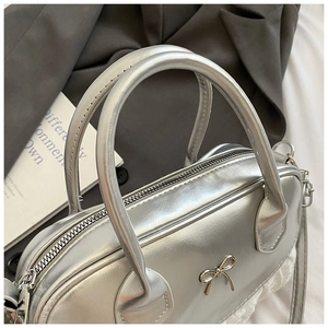 Dettaglio della borsa Boston argento con fiocco in metallo e bordo in pizzo bianco