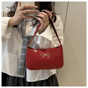 Detailed macro view of red lychee texture leather underarm bag with gold bow clasp