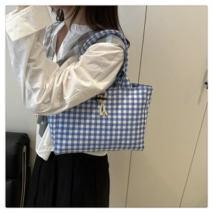Dettaglio della borsa tote in tela a scacchi blu con chiusura a alamaro in corno nero e corda