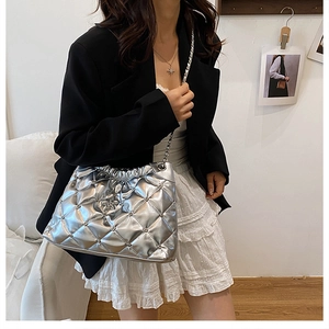 Close-up of metallic silver quilted crossbody bag with star charm and chain strap detail