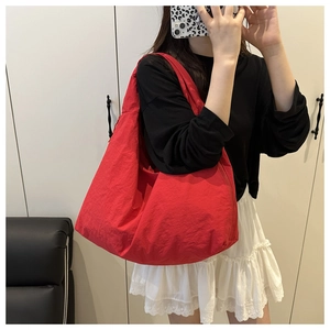 Detailed view of a large red nylon tote bag shown on a model in a home setting