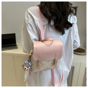 Detailed view of pink patterned mini backpack with bear charm on a female model