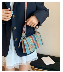 Detail of colorful woven straw crossbody bag with golden clasp and vertical stripes