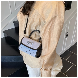 Detailed side view of light blue heart-patterned small square crossbody bag with silver bow