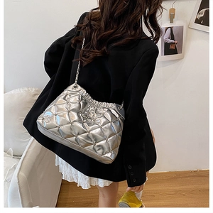 Detail of silver quilted chain bag with metallic finish and metal stud accents