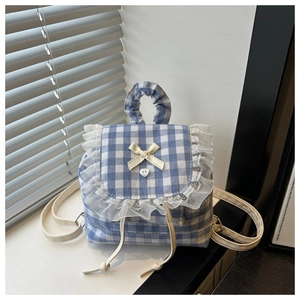 Detail of blue and white gingham backpack featuring lace edges and yellow bow detail