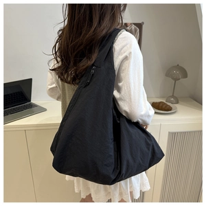 Minimalist black large capacity hobo shoulder bag shown in a cozy indoor commute scene