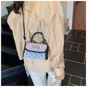 Detail of silver metal bow buckle on light blue striped small square shoulder bag