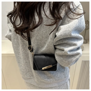 Rear view of a mini black crossbody bag with adjustable strap and gold metal buckle detail
