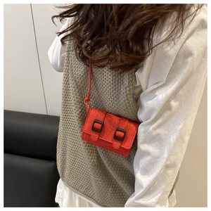 Dettaglio di una mini borsa a tracolla rossa in pelle litchi indossata su un outfit casual