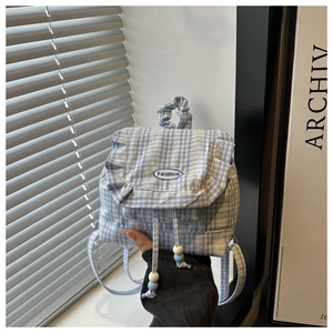 Detail of blue plaid backpack featuring ruffled edges and FASHION embroidered patch