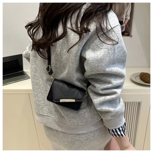 Detailed side view of mini black leather crossbody bag with gold metal trim and strap buckle