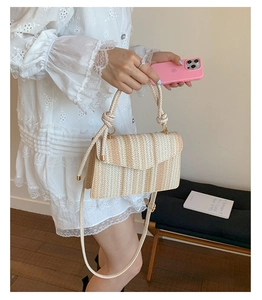 Detail of woven straw crossbody bag featuring white and brown stripes with thick rope handle