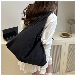 Detail of a large black tote bag with zipper closure and slouchy casual style texture