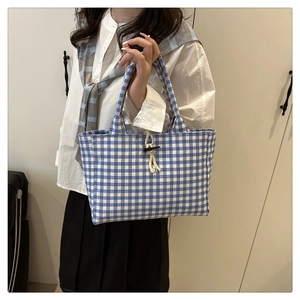 Dettaglio borsa tote in tela a quadretti blu con bottone in legno e chiusura a corda