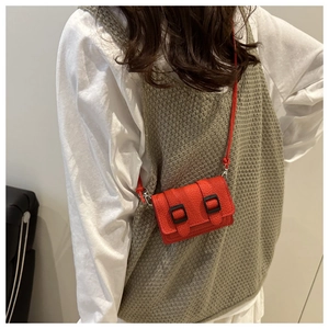 Dettaglio mini borsa rossa in pelle a grana con fibbie nere e tracolla sottile elegante
