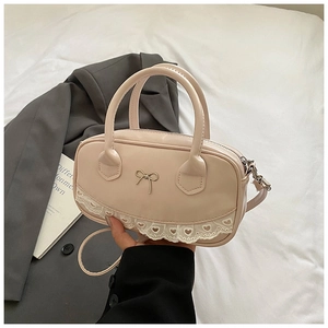 Dettaglio borsa Boston rosa con fiocco in metallo e bordo in pizzo bianco con cuori