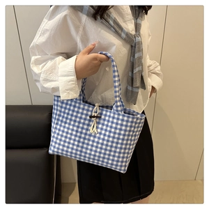 Dettaglio della borsa tote in tela a quadri blu con corda beige e bottone in corno