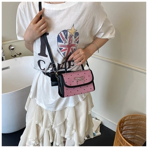 Pink crossbody bag with heart pattern and bow buckle shown on a female model
