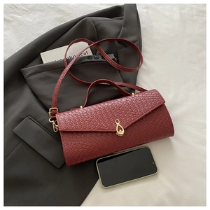 Dettaglio borsa bordeaux con trama intrecciata, chiusura dorata e tracolla in pelle