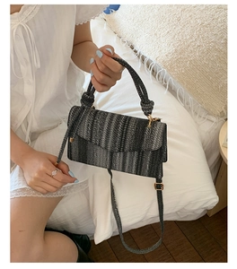 Detail of woven textured shoulder bag with black and gray stripes and a knotted handle