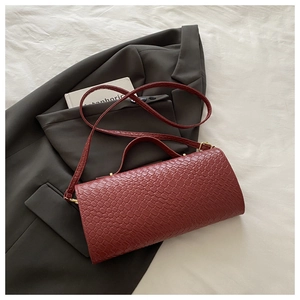 Dettaglio borsa intrecciata bordeaux su abito grigio con finiture dorate eleganti