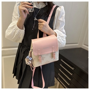 Detail of a mini pink and cream backpack with floral print and a plush rabbit charm