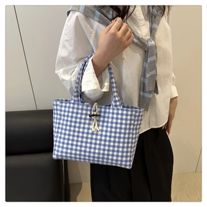 Dettaglio della borsa tote a quadretti blu con bottone in legno e chiusura in corda