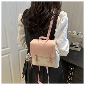 Close-up of pink and cream mini backpack featuring butterfly textures and plush pendant