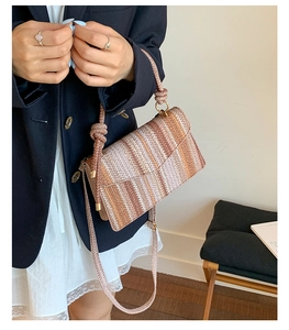 Detail of hand-woven striped shoulder bag with knotted strap and gold metal hardware