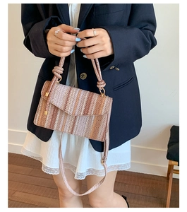 Detail of bohemian striped woven bag with textured straw pattern and long shoulder strap