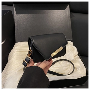 Detail of mini black crossbody bag in gift box with gold metal clasp and adjustable strap