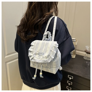 Detail of light blue plaid mini backpack with lace trim and beaded drawstring closure