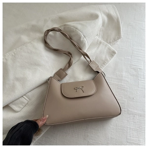 Close-up of a vintage beige underarm bag featuring a silver bow buckle and woven strap