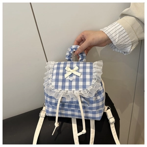 Detail of blue plaid backpack with lace trim, yellow bow, and adjustable white straps