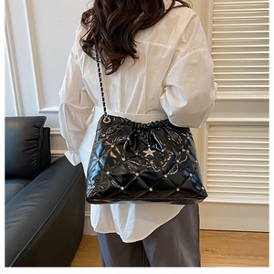 Detail of black quilted leather bucket bag with silver star and rhinestone studs